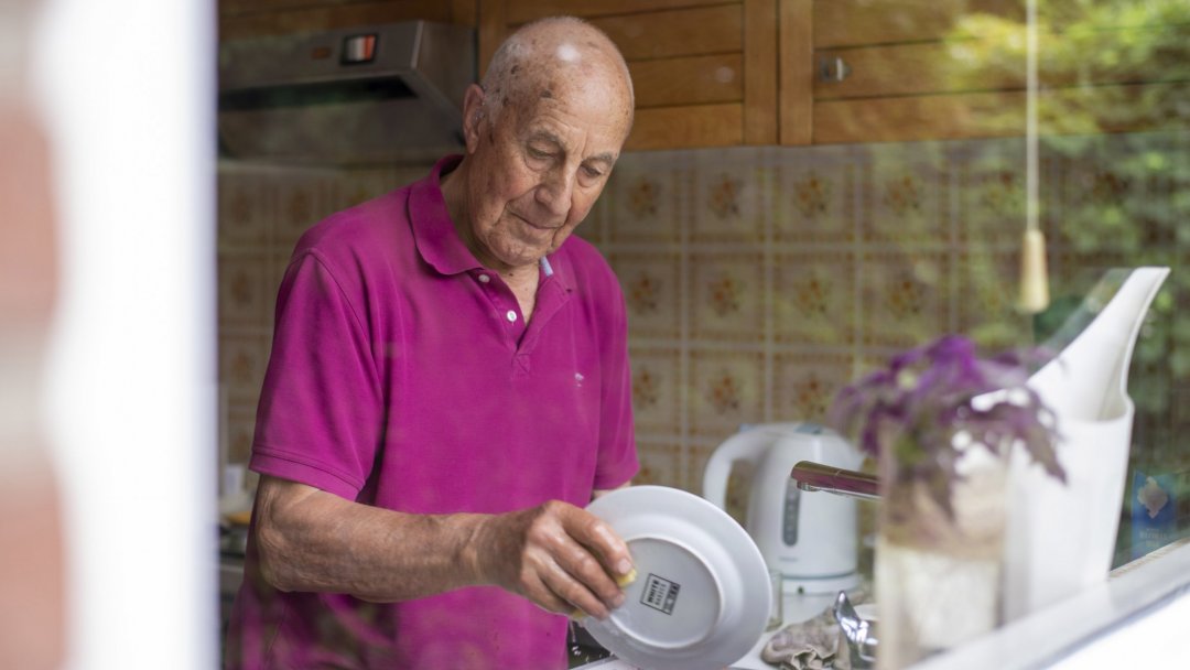 Man doet afwas achter het raam